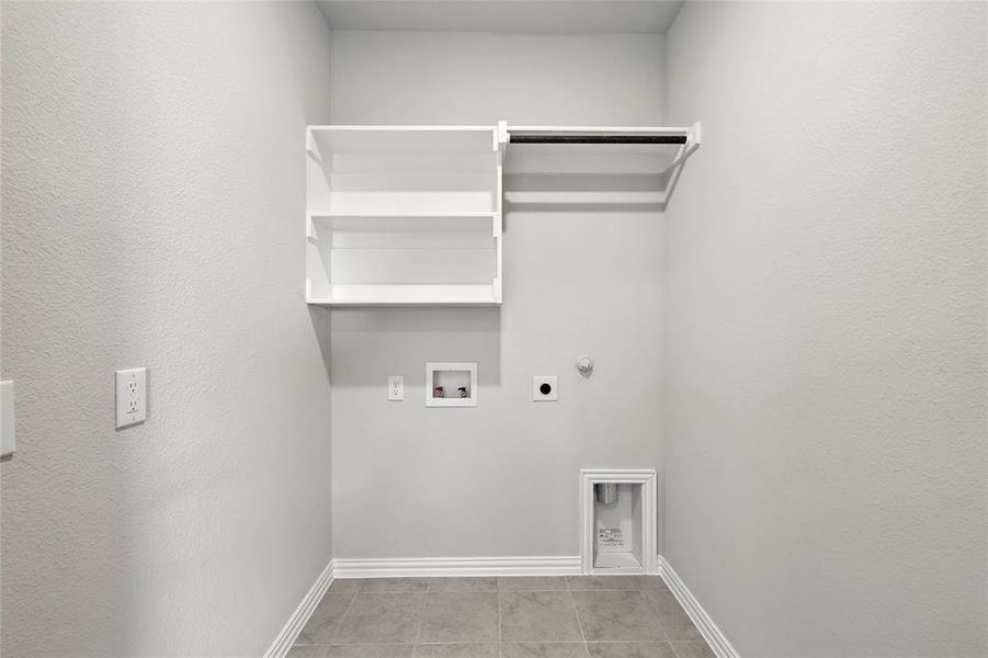 Washroom featuring hookup for an electric dryer, washer hookup, gas dryer hookup, and light tile patterned floors Washroom featuring hookup for an electric dryer, washer hookup, gas dryer hookup, and light tile patterned floors