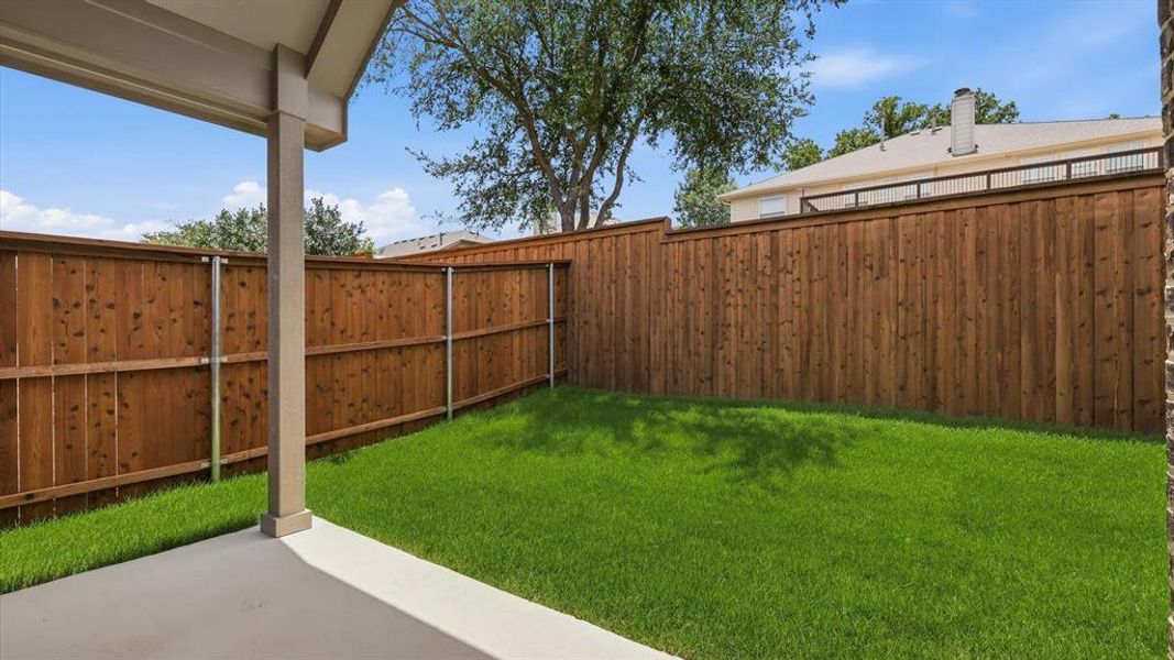 Covered patio featuring a concrete slab and support columns, overlooking a manicured lawn Covered patio featuring a concrete slab and support columns, overlooking a manicured lawn