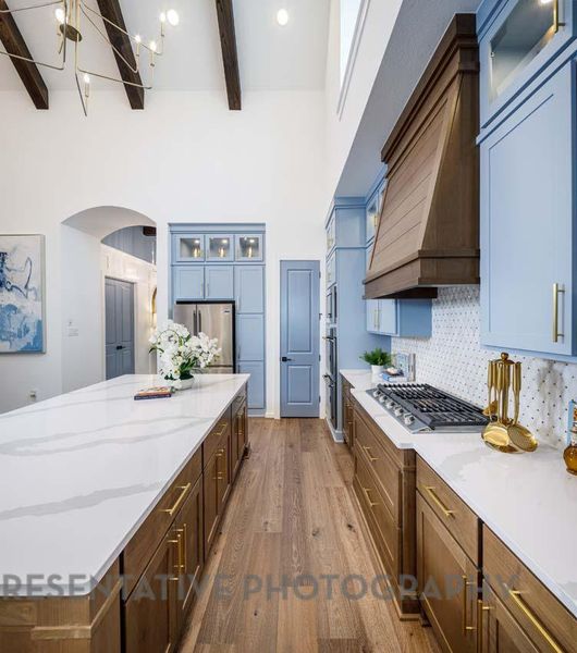 Kitchen with stainless steel appliances, beamed ceiling, a spacious island, arched walkways, and dark wood-type flooring Kitchen with stainless steel appliances, beamed ceiling, a spacious island, arched walkways, and dark wood-type flooring