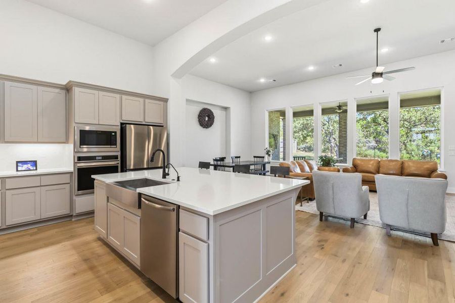 An open concept kitchen flows seamlessly into the living space, featuring abundant natural light and rich wood flooring.