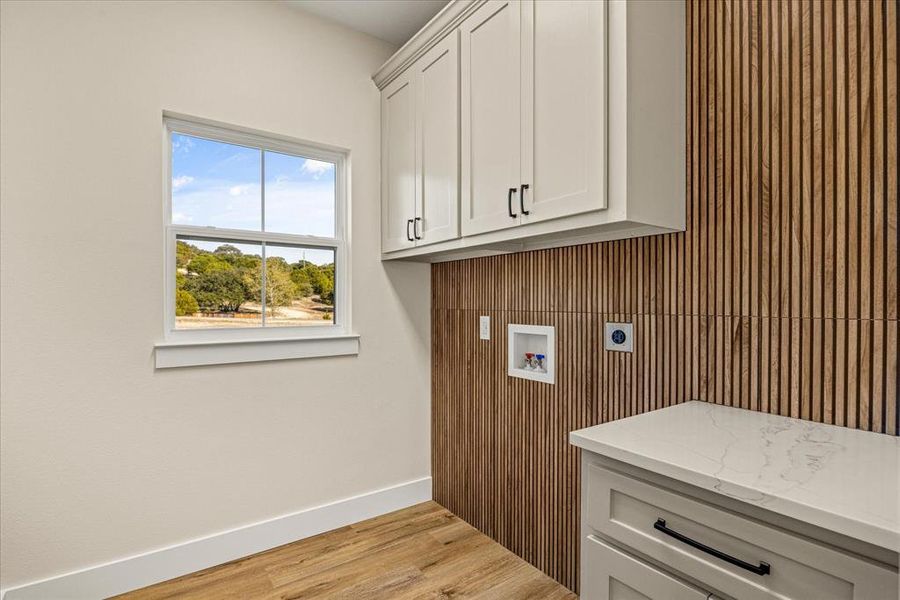 Laundry room featuring hookup for a washing machine, light wood-type flooring, electric dryer hookup, and cabinet space