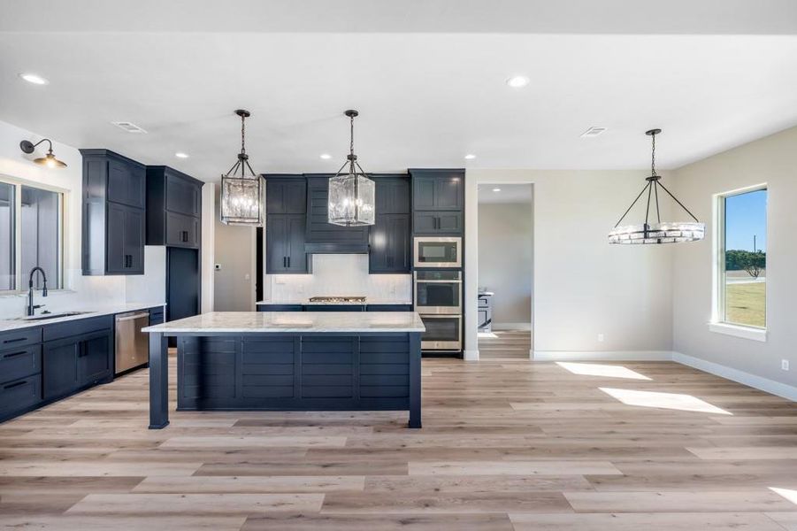 Kitchen with pendant lighting, a center island, sink, and stainless steel appliances