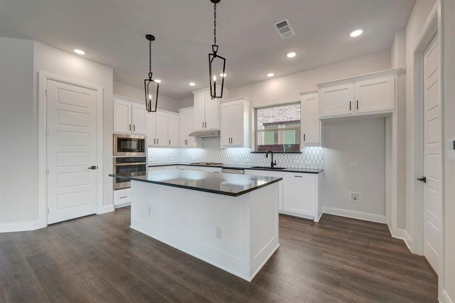 Kitchen featuring backsplash, white cabinetry, a kitchen island, stainless steel appliances, and dark wood-type flooring