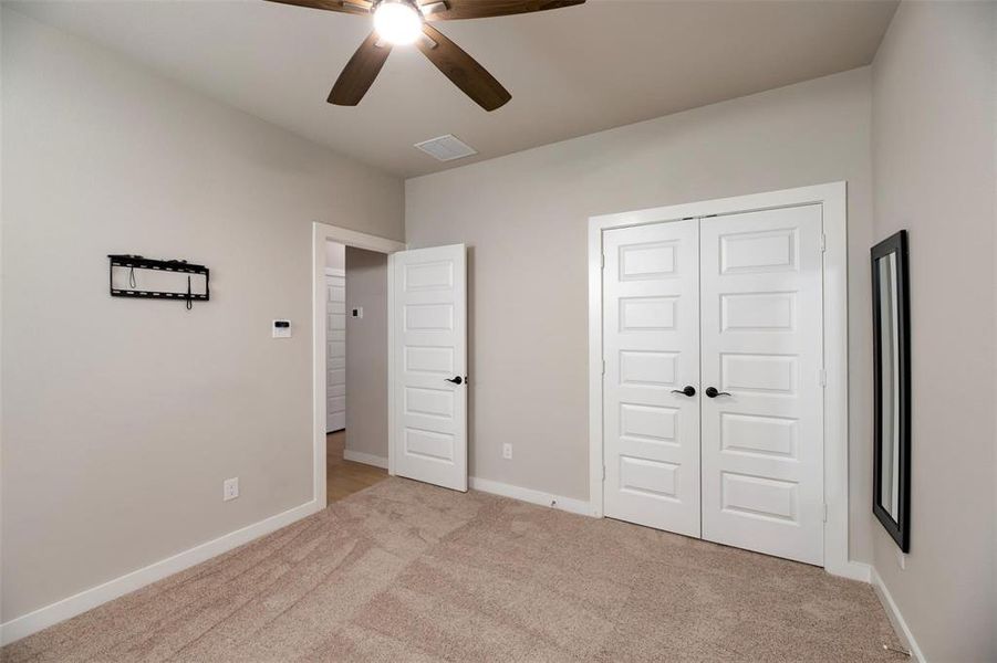 Unfurnished bedroom featuring light carpet, ceiling fan, and a closet Unfurnished bedroom featuring light carpet, ceiling fan, and a closet