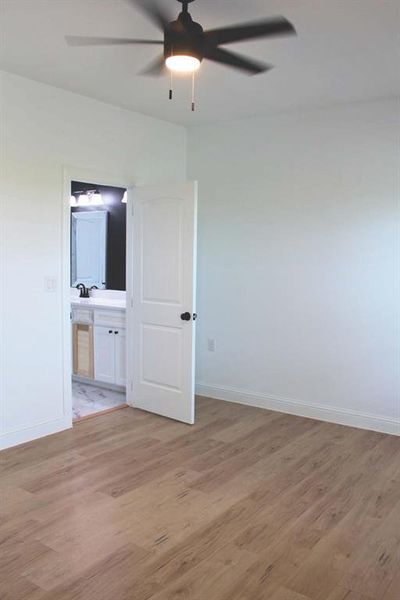 Bedroom with light wood-type flooring, a ceiling fan, and ensuite bathroom Bedroom with light wood-type flooring, a ceiling fan, and ensuite bathroom