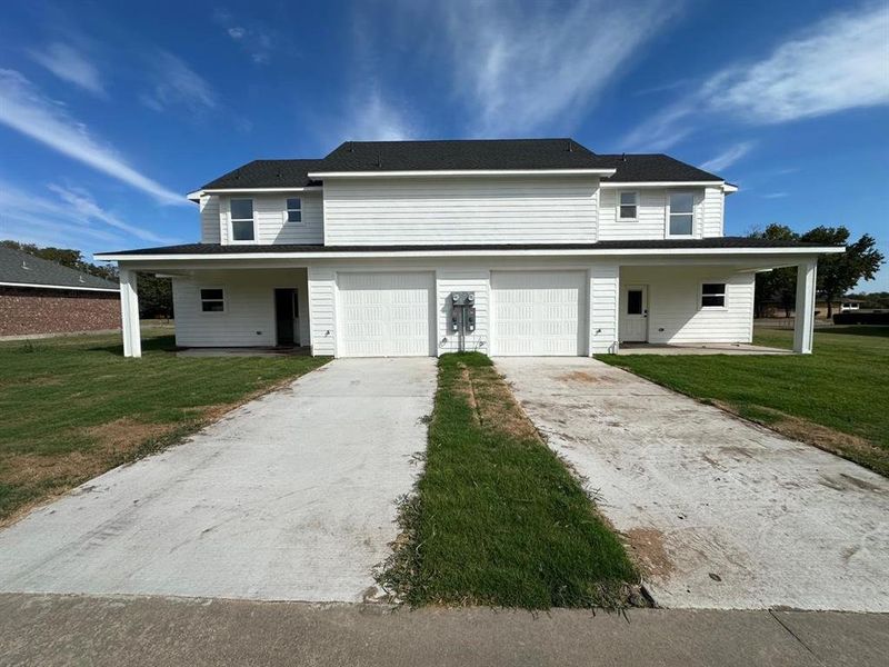 View of front facade featuring a front yard, driveway, and an attached garage
