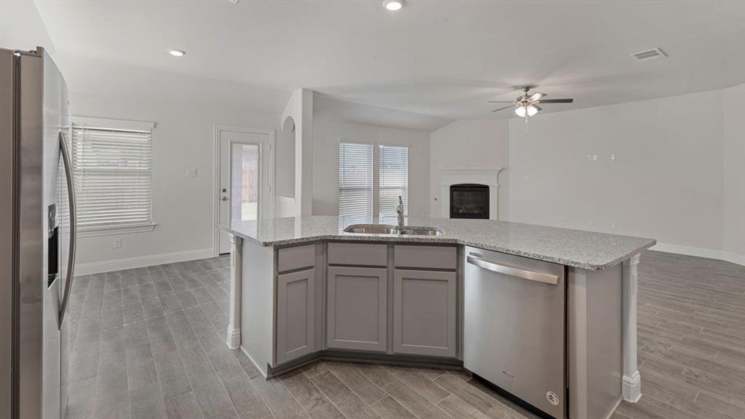 Kitchen featuring stainless steel appliances, gray cabinetry, a kitchen island with sink, wood finish floors, and recessed lighting