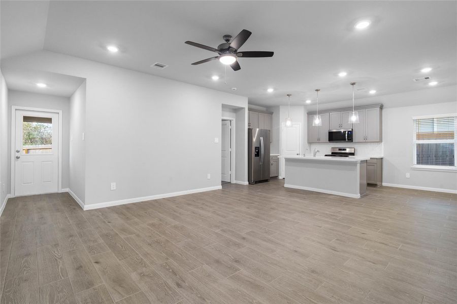 As you step past the entryway, you are immediately welcomed by a bright, open-concept kitchen that serves as the home's focal point. The space feels clean and modern, anchored by a large granite-topped island that seamlessly connects the cooking area to a long, light-filled living space.