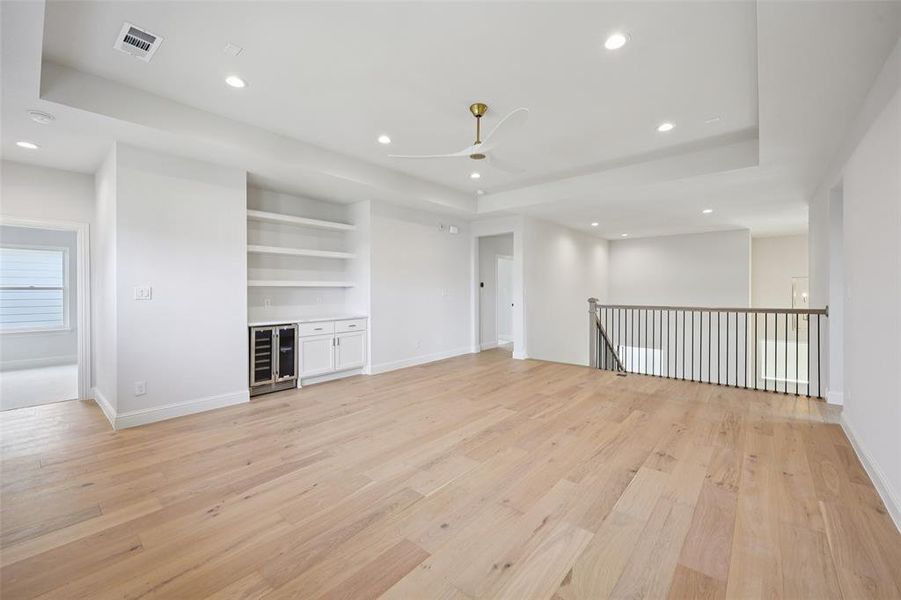 Unfurnished living room with light wood-type flooring, beverage cooler, recessed lighting, a ceiling fan, and built in shelves