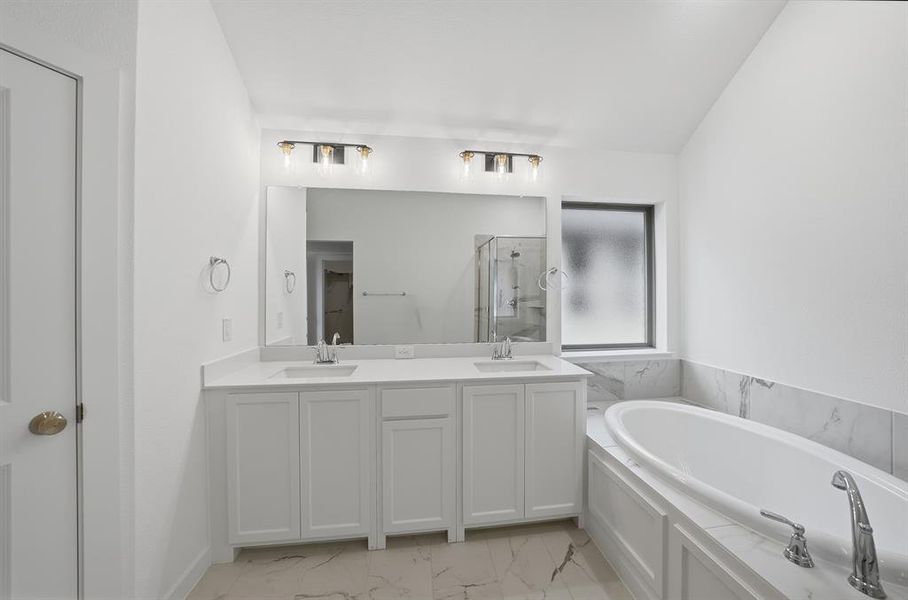 Bathroom with double vanity, a garden tub, a stall shower, and light marble finish flooring