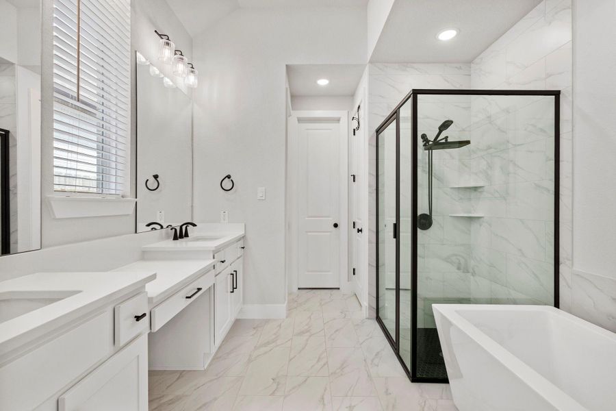 Spa-inspired primary bath with dual vanities, oversized glass shower, and sleek tile finishes.