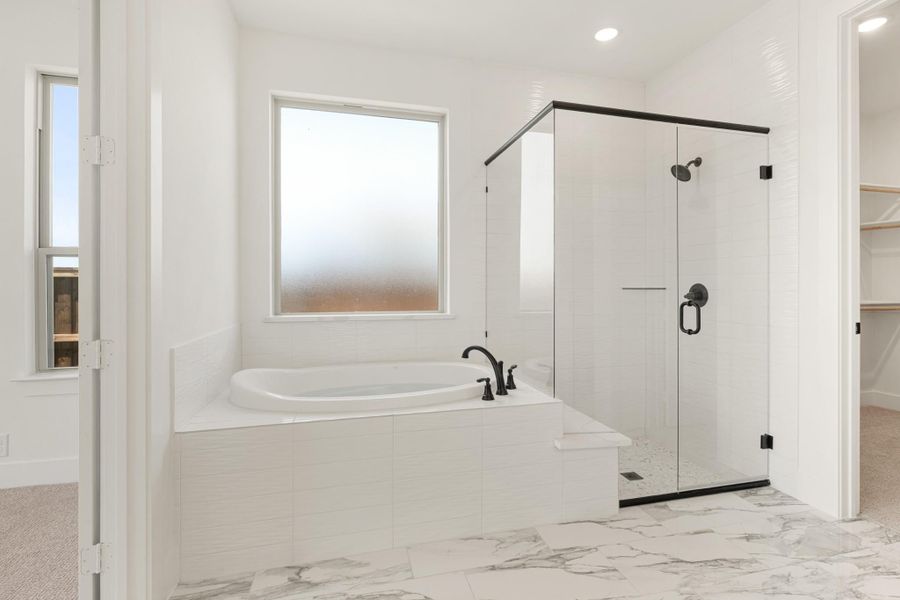 Master bathroom with soaking tub, glass-enclosed shower, and white marble tile floors