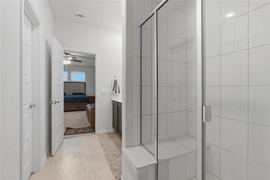 Frameless glass shower enclosure with white tile surround and integrated shower bench