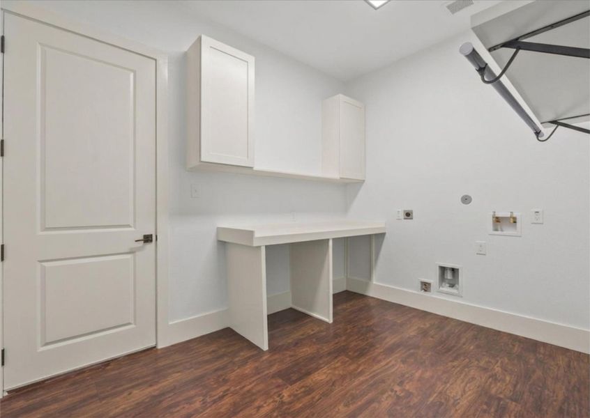 Spacious utility room with built-in cabinetry, folding station, and hanging space.