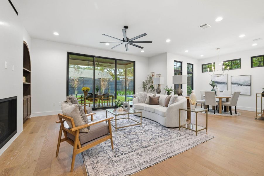 Living room featuring a glass covered fireplace, plenty of natural light, recessed lighting, light wood-style flooring, and a ceiling fan