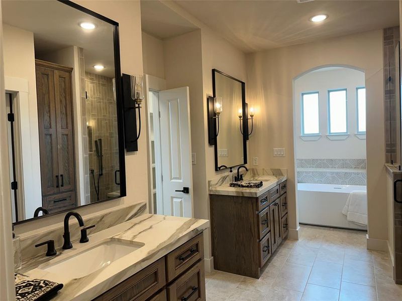 Bathroom featuring dual vanities with stone countertops, individual rectangular sinks, and matte black fixtures