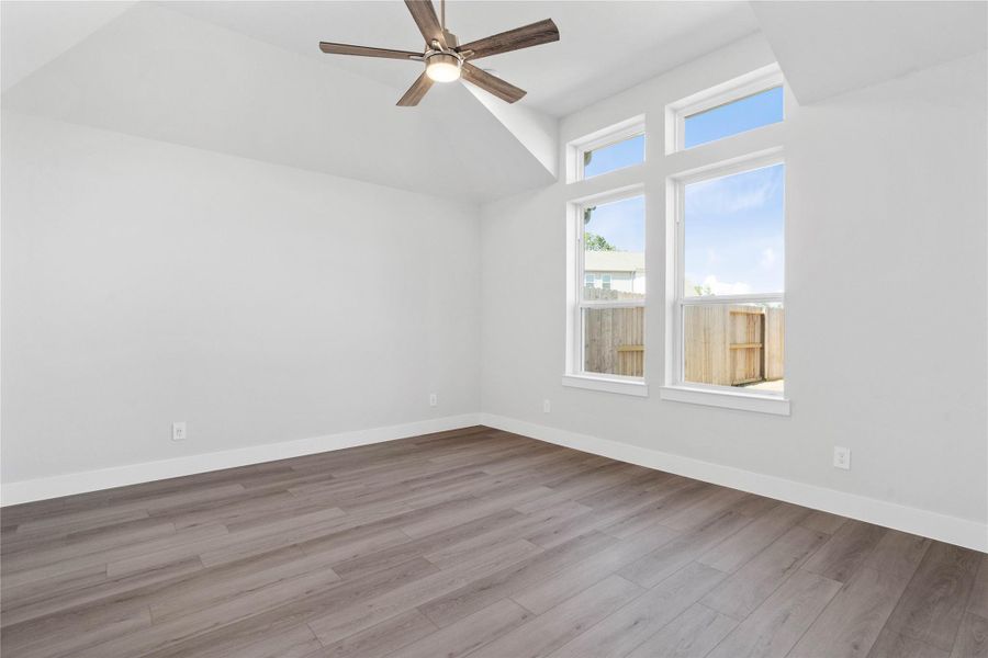 Retreat to this bright and airy primary bedroom, a serene sanctuary designed for ultimate relaxation and comfort. Vaulted ceilings, large windows, stylish LVP flooring, and modern ceiling fan give this room a peaceful space to come home to.