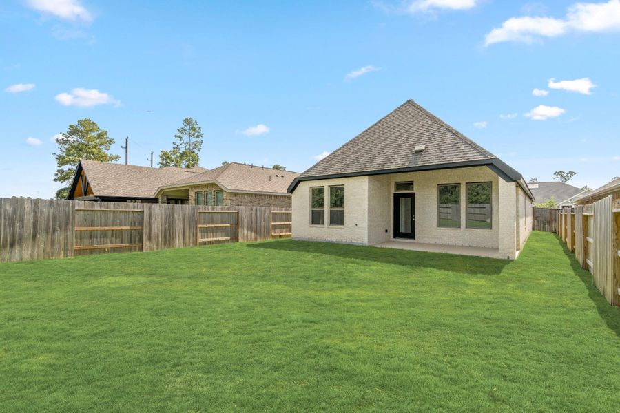 Spacious fenced backyard with green lawn and no immediate rear home directly behind the property.