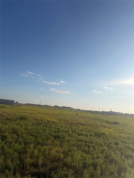 Wide grassy acreage stretches out under an expansive clear blue sky.