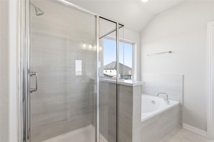 Bathroom featuring a stall shower, a bath, light tile patterned floors, and vaulted ceiling
