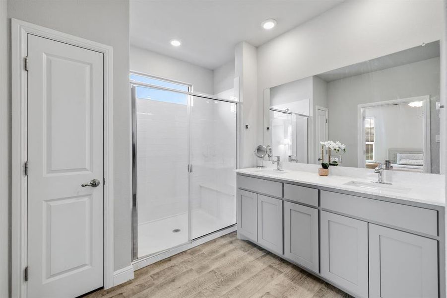 Bathroom with double vanity, a shower stall, and wood finished floors