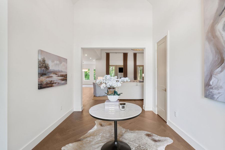 Striking entryway that sets the tone the moment you walk in. Tall ceilings and a wide, open passage create an immediate sense of scale, while warm wood flooring carries your eye straight into the main living area.