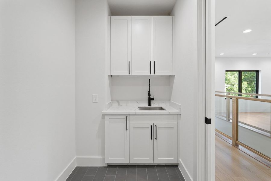 Cabinet storage and an under-mount stainless steel sink outfit the laundry room a few steps from the Primary.