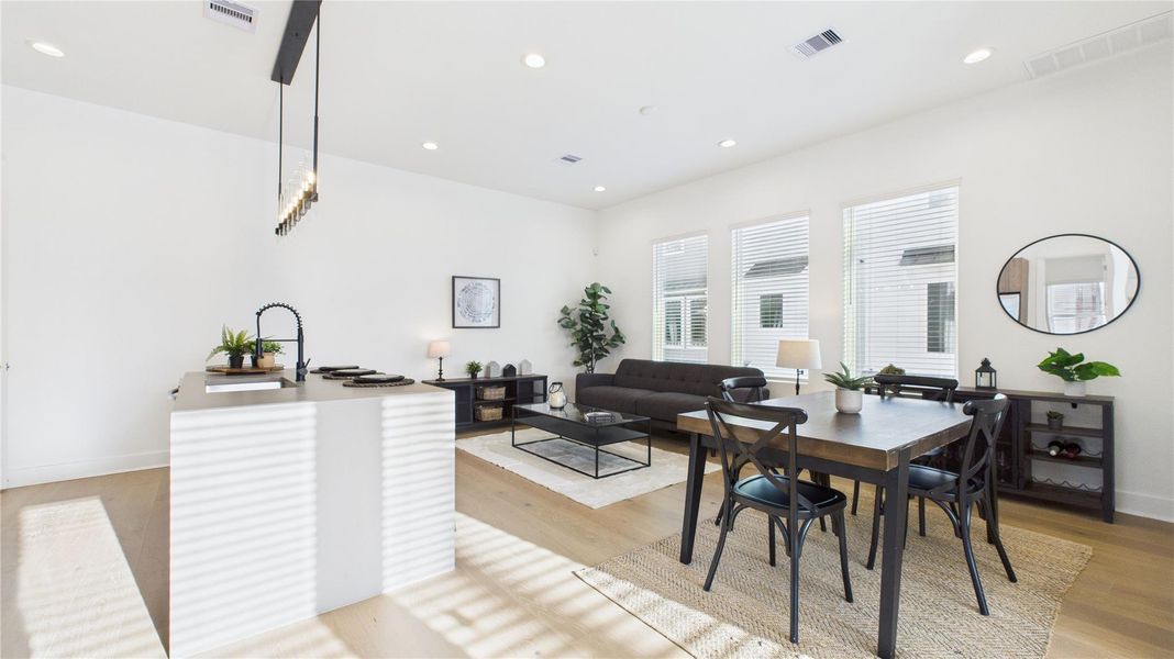 The welcoming second-floor open-concept living area seamlessly combines the living room, dining room, and kitchen, filled with natural light and enhanced by modern finishes and engineered hardwood flooring throughout, creating a bright and inviting space ideal for everyday living and entertaining.