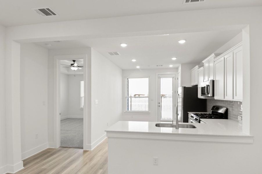 Kitchen with light stone countertops, white cabinetry, stainless steel appliances, light wood-style flooring, and recessed lighting