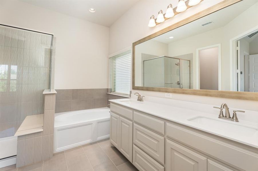 Bathroom featuring a stall shower, a garden tub, light tile patterned floors, double vanity, and recessed lighting