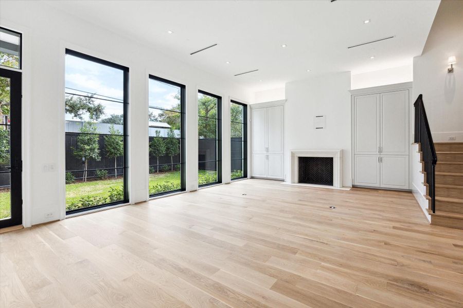 [Living Room]A Napolean gas log fireplace with limestone mantel, flanked by floor-to ceiling cabinets, anchors the rear wall of the living room.