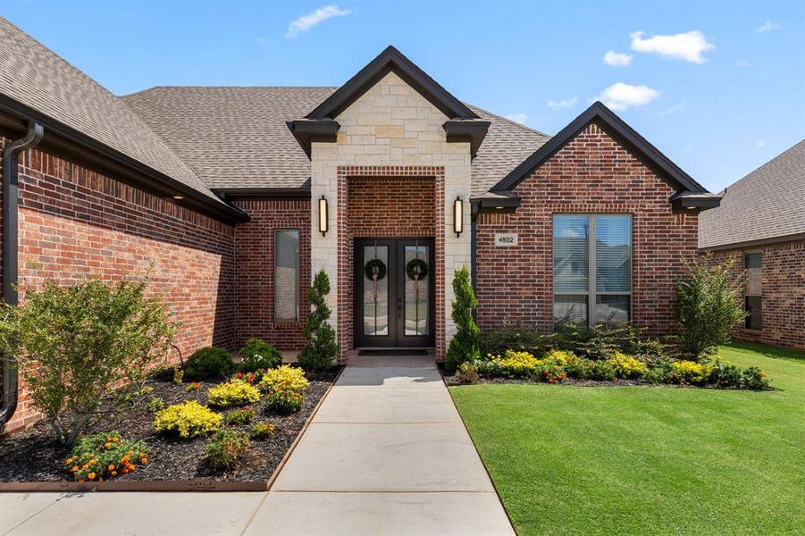 View of exterior entry with roof with shingles, french doors, brick siding, and a lawn View of exterior entry with roof with shingles, french doors, brick siding, and a lawn