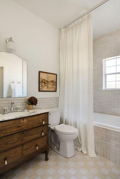 Full bathroom featuring tiled shower / bath, vanity, and backsplash