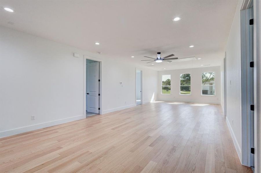 Spacious room featuring wood-finish flooring, recessed lighting, and a contemporary ceiling fan Spacious room featuring wood-finish flooring, recessed lighting, and a contemporary ceiling fan