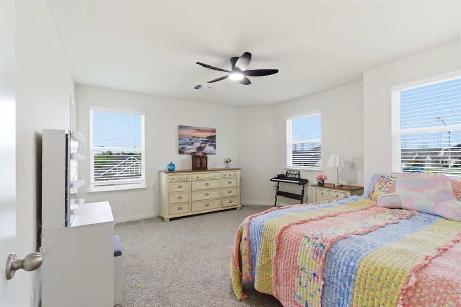 This room features neutral-toned carpet, white walls, and bright windows with blinds