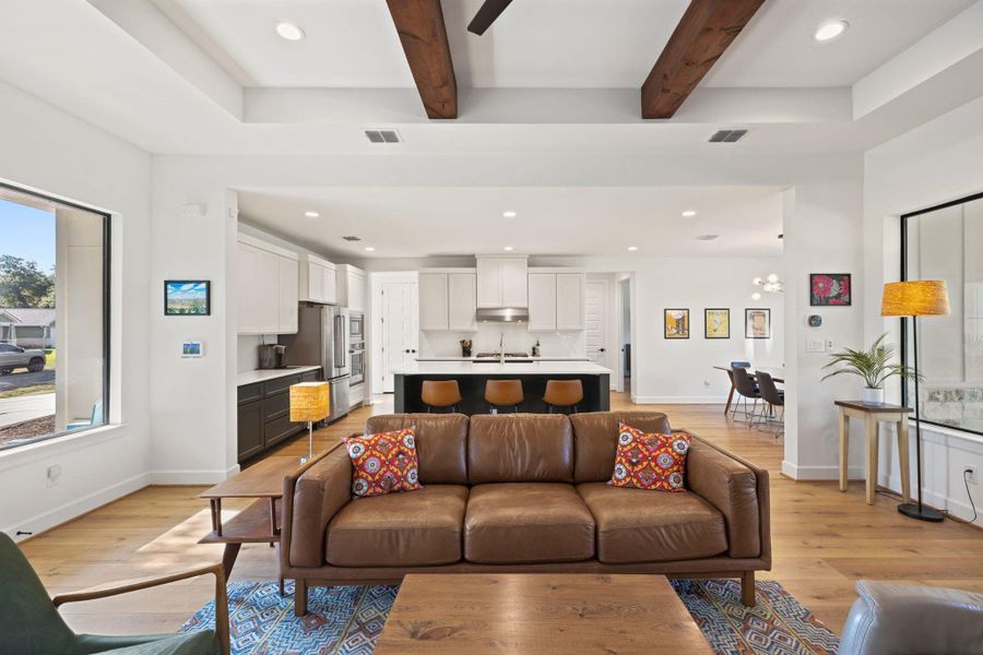 Living room with plenty of natural light, recessed lighting, beam ceiling, light wood-style floors, and a chandelier