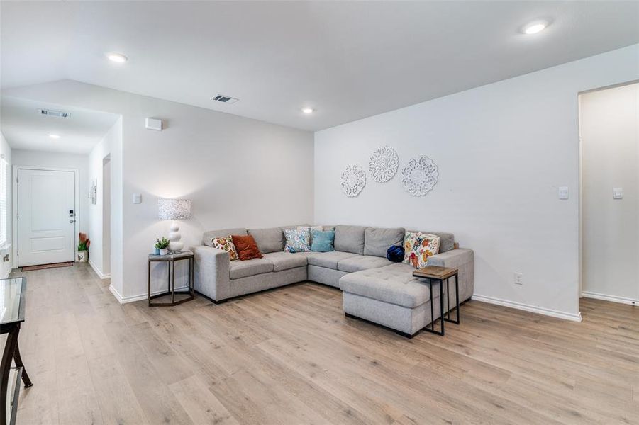 Living area with lofted ceiling, visible vents, light wood-style flooring, and recessed lighting