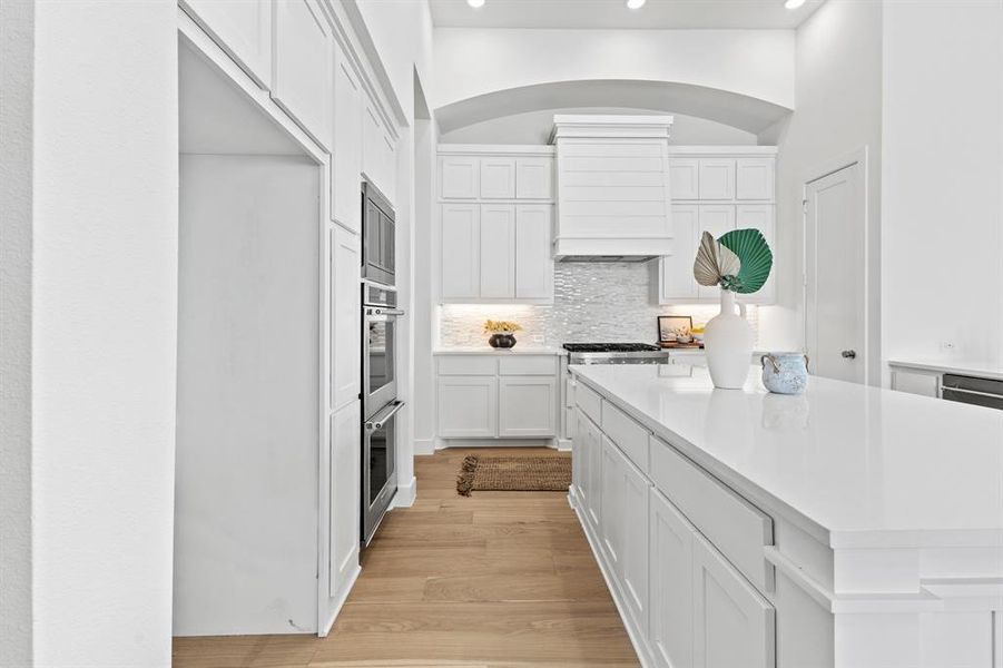 Kitchen with white cabinetry, decorative backsplash, light wood finished floors, a center island, and recessed lighting
