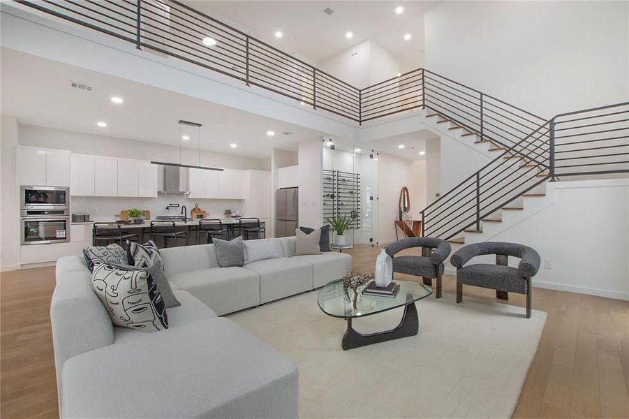 Living room featuring light hardwood / wood-style flooring, sink, and a high ceiling