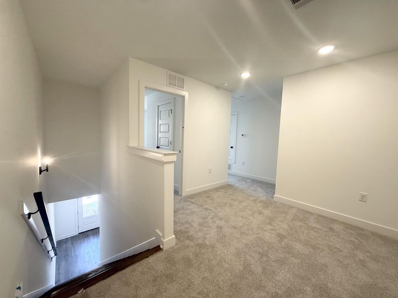Hallway with an upstairs landing, carpet, and recessed lighting