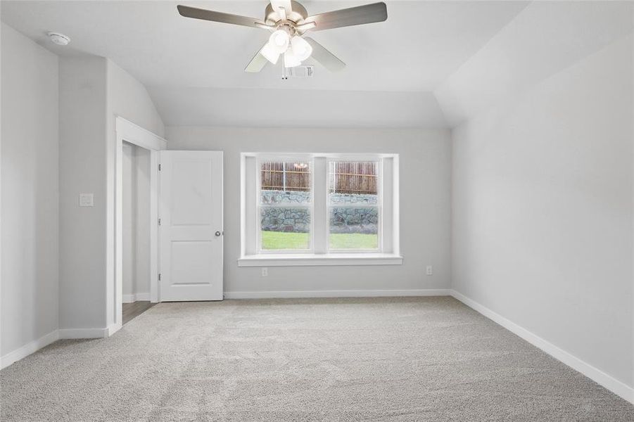 Carpeted empty room featuring a smoke detector, ceiling fan, and lofted ceiling Carpeted empty room featuring a smoke detector, ceiling fan, and lofted ceiling