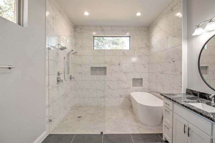 Bathroom with tile patterned floors, vanity, shower with separate bathtub, and tile walls