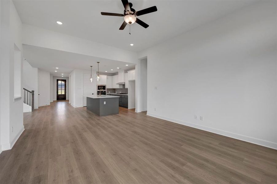 Expansive open-concept living area featuring hardwood-style flooring, recessed lighting, and a ceiling fan