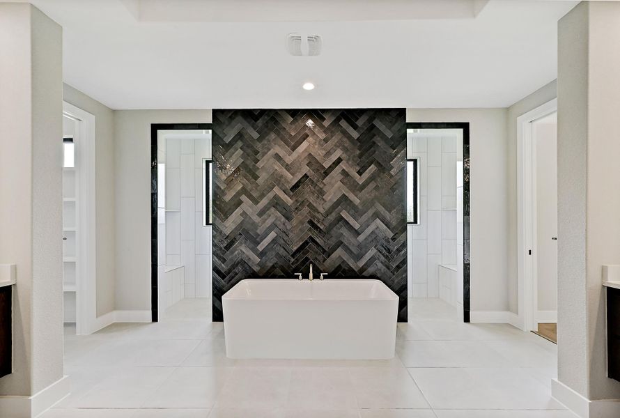 A freestanding soaking tub takes center stage, surrounded by striking herringbone tile.