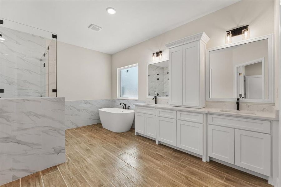 Full bathroom featuring double vanity, tile walls, a marble finish shower, a freestanding tub, and wood tiled floors