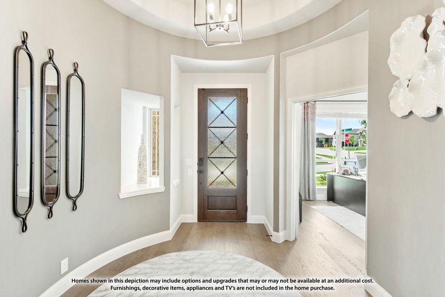 Curved foyer with wood front door, glass panels, pendant light, and light hardwood floors
