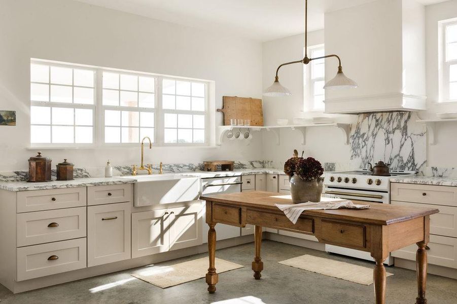 Kitchen with concrete flooring, light stone counters, white electric stove, and healthy amount of natural light