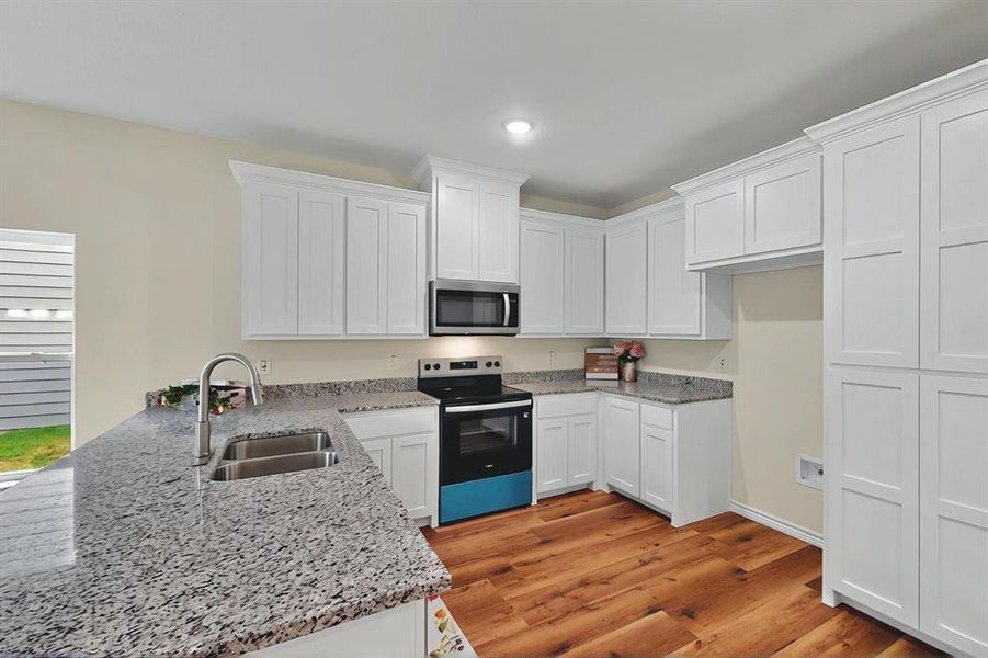 Kitchen with black / electric stove, a sink, stainless steel microwave, a peninsula, and recessed lighting Kitchen with black / electric stove, a sink, stainless steel microwave, a peninsula, and recessed lighting