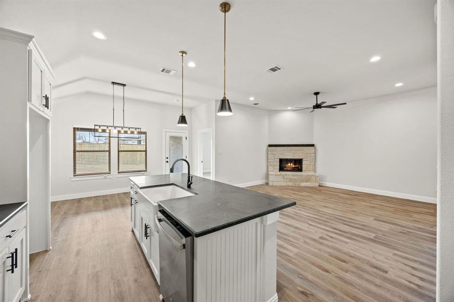 Kitchen featuring white cabinetry, open floor plan, a fireplace, stainless steel dishwasher, and recessed lighting