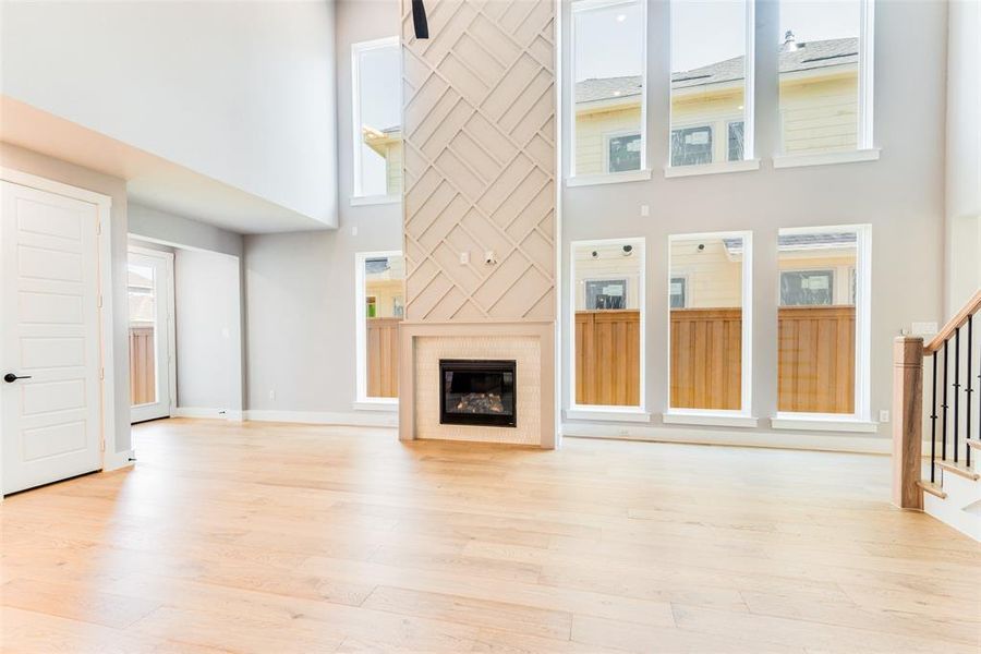 Unfurnished living room featuring a high ceiling and light wood-type flooring